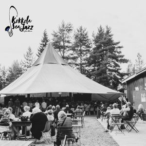 Kuva on otettu Kokkola sea Jazz -festivaalilla. Kuvassa näkyy esiintymiskato, sirkusteltta, sekä konsertissa olevia ihmisiä Kahvila sahan pihapiirissä.